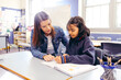 © Austockphoto - Aboriginal female school teacher sitting with her student in the classroom