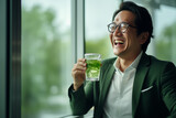 Asian male employee holding green healthy fruit and vegetable juice in the office