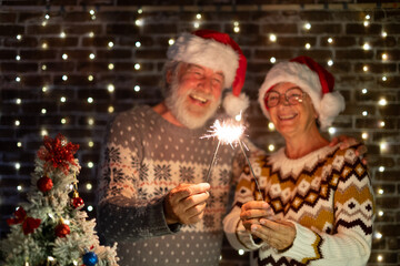 Wall Mural - Happy senior family couple in Santa hat celebrate together with love Christmas and new year event night firing sparklers. Man and woman enjoy magic moment relationship at Christmas time