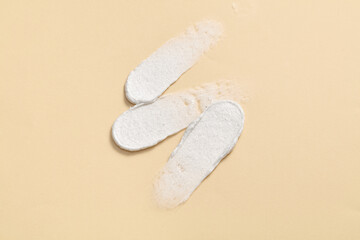 Wall Mural - Top view of cream smears on light background. A skincare product sample, including moisturizer and exfoliating cream. Scene for advertising, showcasing the textures.