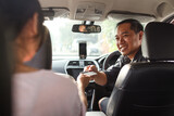 Fototapeta  - Passenger of online taxi making payment through credit card. Cashless payment in commercial transportation.