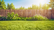 green grass lawn, flowers and wooden fence in spring backyard garden