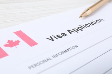 Wall Mural - Immigration to Canada. Visa application form and pen on white wooden table, closeup