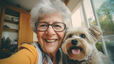 Fototapeta Zwierzęta - copy space, stockphoto, selfie photo taken by a elderly woman with dog cat in the living room. Senior woman using modern technology. Elderly woman taking a selfie with a cellphone, smartphone.