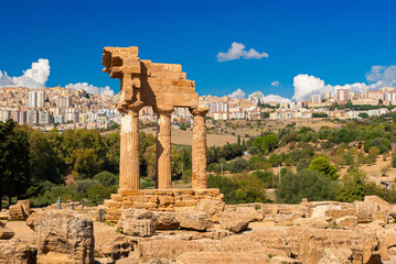 Wall Mural - The temple of Dioscuri in the Valley of the Temples of Agrigento, in Sicily; the modern city in the background