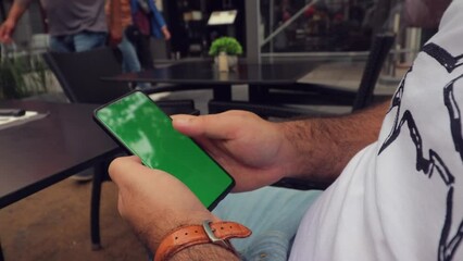 man scrolling phone green screen browsing social media chroma key reading news close up hands. man's