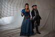 A lady and a pirate in an antique doublet and hat, a couple in pirate costumes. sails on the background