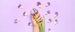Female hand with beautiful manicure and flower on lilac background