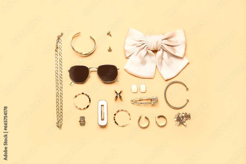 Stylish jewelry with sunglasses on beige background