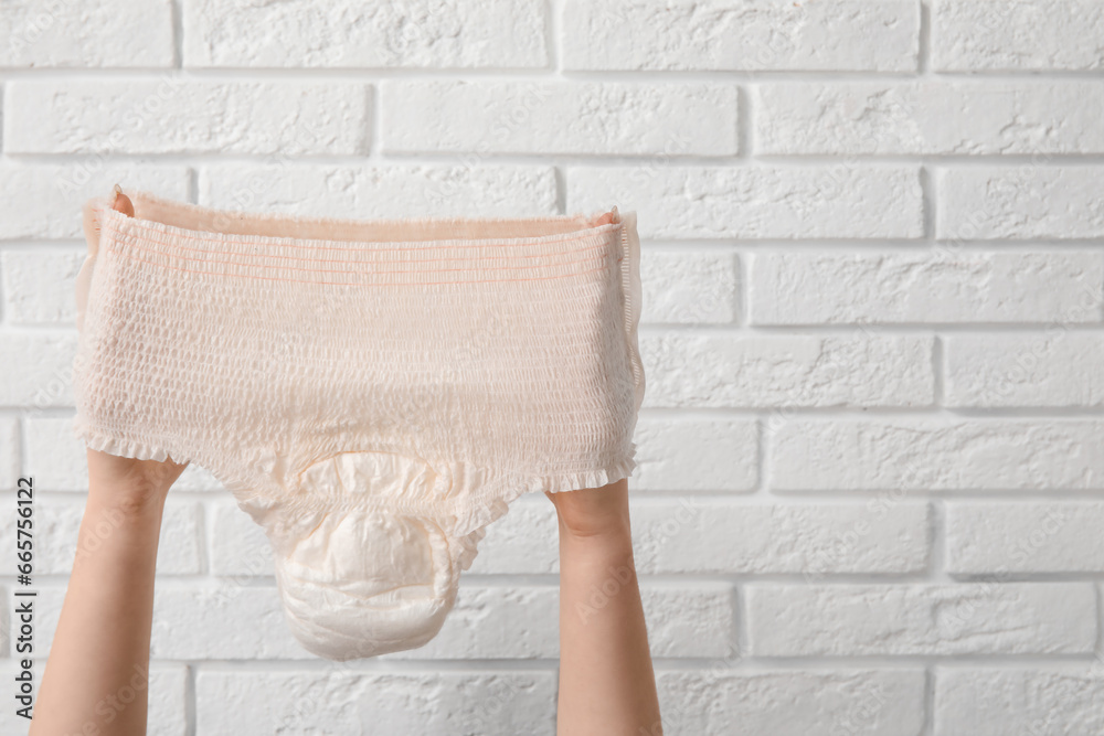 Woman with period panties on white brick background