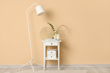 Poster - Beautiful ikebana on table and lamp near beige wall in room