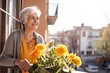 © Andrii Zastrozhnov - A happy senior Caucasian woman enjoying the outdoors, with a bouquet of yellow flowers during summer.