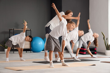 Poster - Female yoga instructor with group of little children in gym