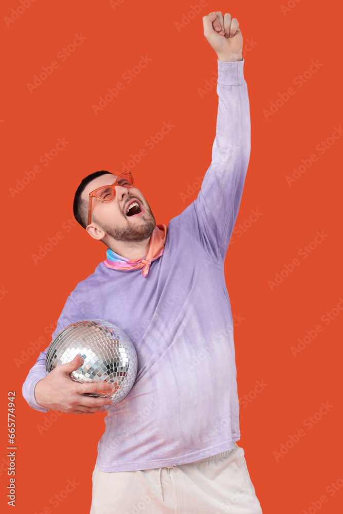 Handsome young man with disco ball on red background