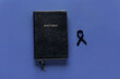 Black funeral ribbon and Holy Bible on blue background
