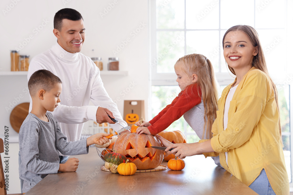 Happy family carving Halloween pumpkin in kitchen