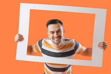 Canvas Print - Happy young man with frame on orange background