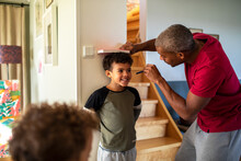 African American father measuring sons height and marking it on the wall in the living room