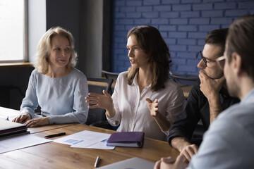 Wall Mural - Young attractive woman team leader lead training in modern office, teach audience at seminar. Serious businesswoman discuss project plan at group briefing in boardroom. Business, teamwork, negotiation