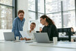 © Kostiantyn - Group of young business people discussing something and smiling while sitting at the office table