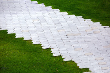 Wall Mural - pavement with granite tiles honeycomb pattern and green lawn on summer park, nobody.