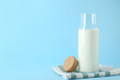 Glass carafe of fresh milk and lid on light blue background, space for text