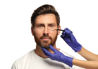 Poster - Man preparing for cosmetic surgery, white background. Doctor drawing markings on his face, closeup