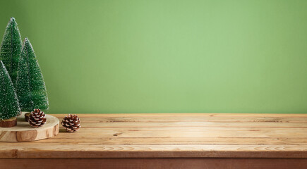 Wall Mural - Empty wooden table with pine tree decoration over green background.  Christmas and winter holidays mock up for design and product display