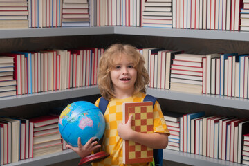 School boy with world globe and chess, childhood. Back to school. Funny little child from elementary school with book. Education. Kid study and learning.