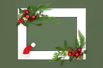 Wall Mural - Christmas Eve santa hat, baubles and winter flora background border with white frame on green. Abstract design for greeting card, label, invitation, menu, gift tag.