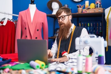 Poster - Young redhead man tailor using laptop at clothing factory