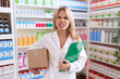 Young caucasian woman working at pharmacy drugstore holding box doing inventory angry and mad screaming frustrated and furious, shouting with anger looking up.