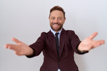 Poster - Middle age business man with beard wearing suit and tie looking at the camera smiling with open arms for hug. cheerful expression embracing happiness.