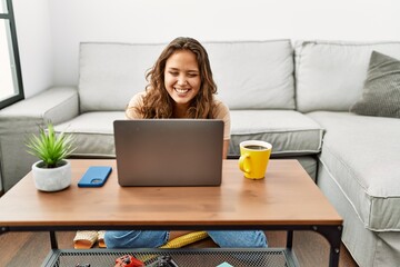 Canvas Print - Young beautiful hispanic woman using laptop sitting on floor at home