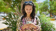 © Krakenimages.com - Young beautiful hispanic woman using smartphone smiling at park