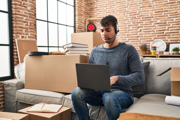 Poster - Young hispanic man working with laptop at new home thinking attitude and sober expression looking self confident