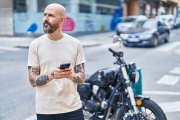 Canvas Print - Young bald man using smartphone with serious expression at street