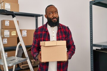 Poster - African american man working at small business ecommerce smiling looking to the side and staring away thinking.