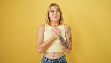 Wall Mural - Young blonde woman smiling confident thinking over isolated yellow background