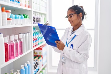 Canvas Print - Young beautiful hispanic woman pharmacist writing on document at pharmacy