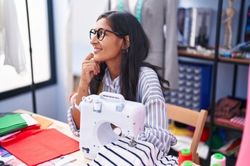 Sticker - Young beautiful hispanic woman tailor smiling confident sitting on table at clothing factory