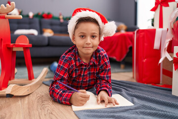 Canvas Print - Adorable hispanic boy writing santa claus letter sitting by christmas tree at home