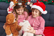 © Krakenimages.com - Brother and sister playing with teddy bears sitting on sofa by christmas decoration at home