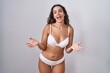 © Krakenimages.com - Young hispanic woman wearing white lingerie smiling cheerful with open arms as friendly welcome, positive and confident greetings