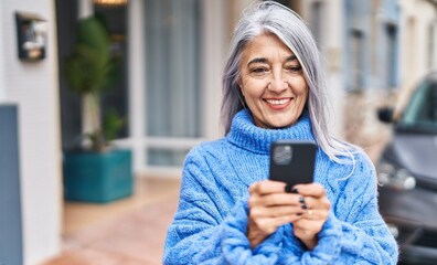 Poster - Middle age grey-haired woman smiling confident using smartphone at street