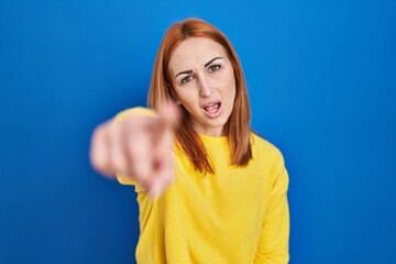 Poster - Young woman standing over blue background pointing displeased and frustrated to the camera, angry and furious with you