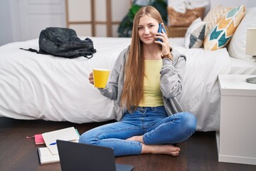 Poster - Young caucasian woman talking on smartphone drinking coffee at bedroom