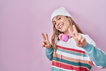 Sticker - Young blonde woman standing over pink background smiling looking to the camera showing fingers doing victory sign. number two.