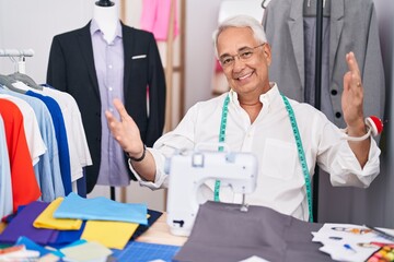 Canvas Print - Middle age man with grey hair dressmaker using sewing machine looking at the camera smiling with open arms for hug. cheerful expression embracing happiness.