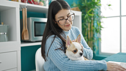 Canvas Print - Young hispanic woman with chihuahua dog hugging siting on the table at dinning room